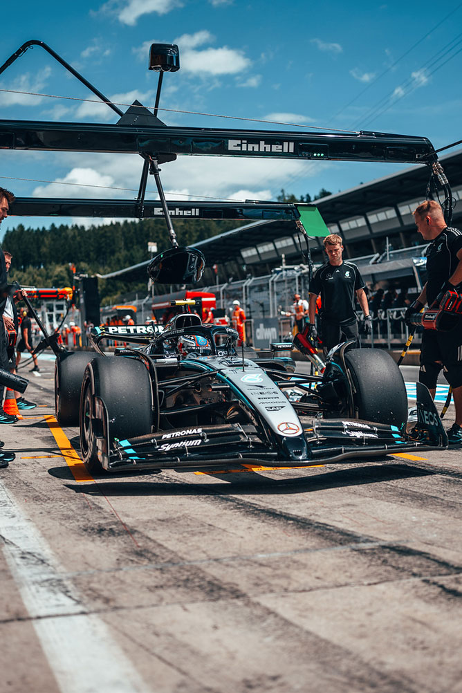 En Mercedes-AMG Formel 1-bil er i pitlane, omgivet af teammedlemmer under en Einhell-garagekonstruktion.